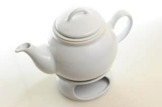 Biały dzbanek z podgrzewaczem i sitkiem do herbaty